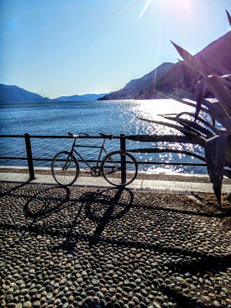 lago azzurro sullo sfondo, bicicletta in primo piano, veduta in profondità dell'orizzonte. Agave in primo piano.