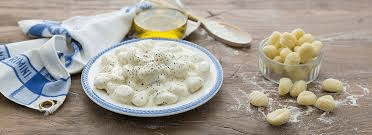 immagine di tavolo da cucina con piatto di gnocchi al gorgonzola ed altri alimenti