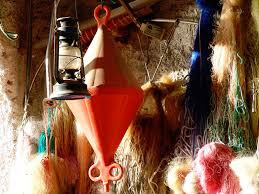 focus su lanterna ad olio appesa, muro con appese reti da pesca di diversi colori